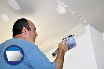 a contractor spackling drywall - with Iowa icon