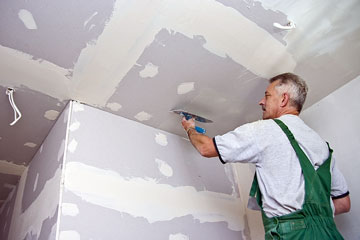 a drywall finisher applying drywall compound on a ceiling
